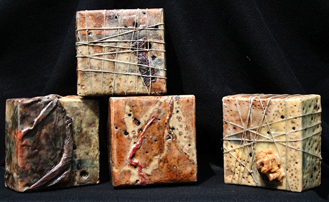 Box covered with various papers, wax, paint rags, and twine with burned-in holes. 