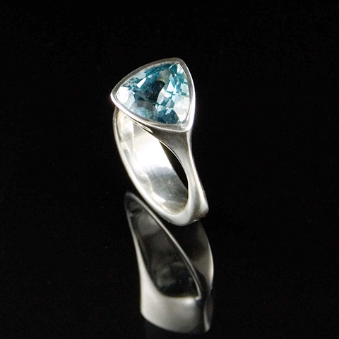Sterling Silver ring with a trillion shaped faceted Swiss Blue Topaz gem stone. The shape of the band follows the contours of the triangular shaped stone.
