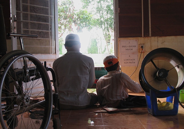 Two young men work at a lathe at a workshop in a rural training facility for victims of Dioxin.