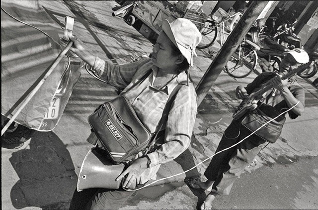 The blind leads the blind:  A musician and his assistant sell lottery tickets in the street, downtown Saigon.