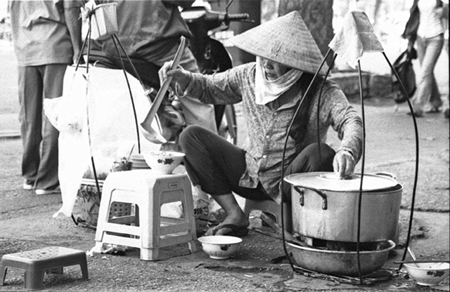 A woman prepares Pho on the street in downtown Saigon.