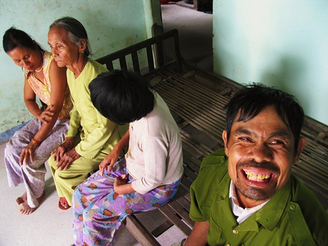 A mother sits with her three developmentally disabled children in their home outside of Danang.