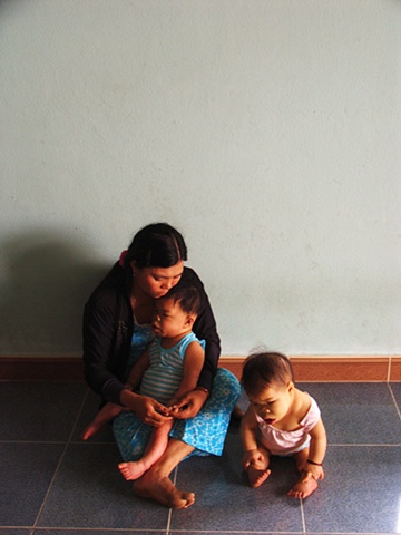 A woman and her two children in their home outside of Danang.  The girl on the floor is nine years old, her brother, in his mother's lap, is ten.
