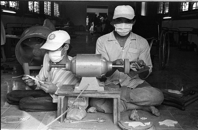 Two boys make tourist trinkets at a facility in charge of helping them gain viable skills.