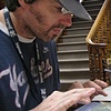Ricky applying lowfire stone surfaced glazes to an outdoor vessel while Lloyd writes historical fiction on his computer.
