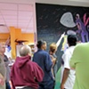 Kimber reading the text on the mural she created for the Blue Sink exhibit.