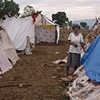 Woman in tent camp among shelters from bed sheets
L&eacute;og&acirc;ne