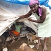 Woman showing her tent camp home
L&eacute;og&acirc;ne