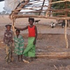 Children under the frame of a hut