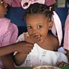 Orphan eating with her hands before spoons are handed out
L&eacute;og&acirc;ne