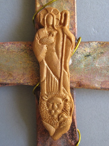 clay shepherd on copper cross close up
