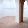 Exhibition Flying Carpet Prayers at El P&oacute;sito, a Catholic prayer for world peace and a Jewish prayer for journeys. On the floor, rolled newspaper from Catalunya in a shape of Ca&ntilde;adas Real